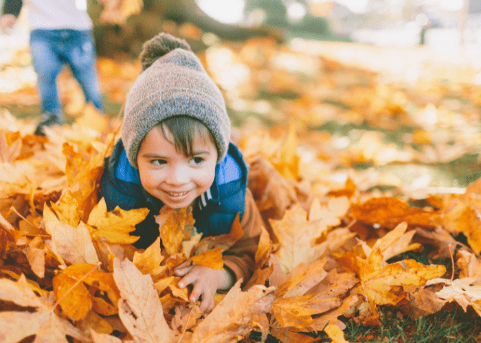 kid jumping in fall leaves